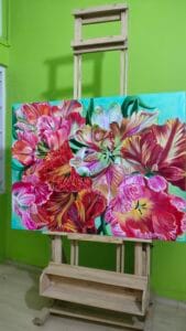 Original parrot tulip painting on easel by Sumana Burman Fine Art – large vibrant acrylic artwork in progress, photorealistic botanical realism painting with vivid red and pink tulip petals.