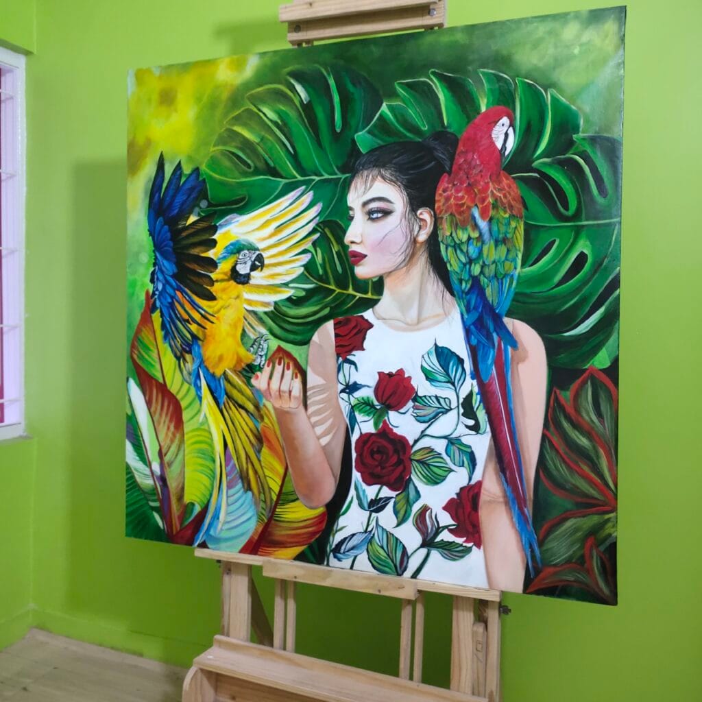 Wilderness – original acrylic painting by Sumana Burman Fine Art featuring a woman with macaw artwork in vibrant tropical foliage, symbolizing harmony between human and nature.