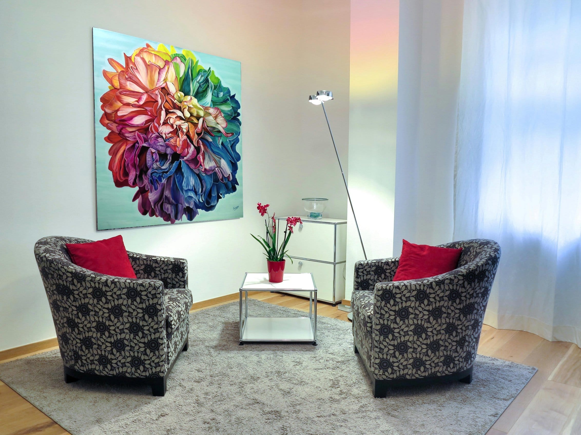 Chromatic Resolve original rainbow peony painting by Sumana Burman displayed in a modern living room interior above two armchairs.